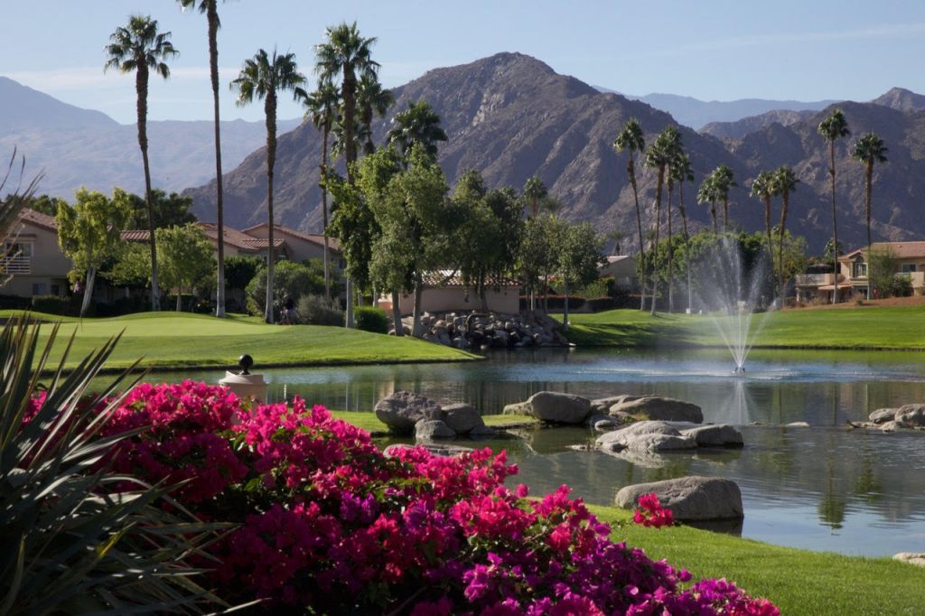 view of golf course green with flowers and mountain