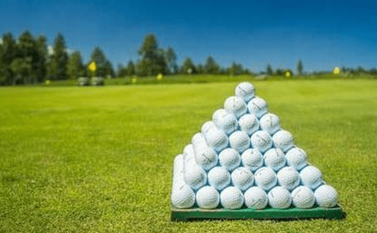 Pyramid of golf balls on golf course driving range