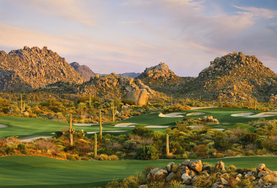 Wide-angle view of multiple fairways with rocky hills in the background coated in large bulders